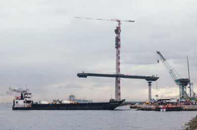 Cranes at commercial dock against sky