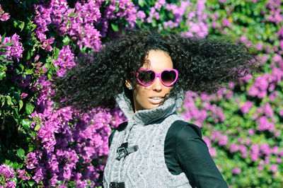 Young woman wearing sunglasses with tousled hair against bougainvillea