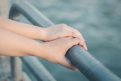 Cropped hands of couple holding railing
