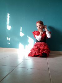 Girl in flamenco dance costume crouching on floor at home