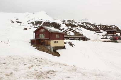 Snow covered houses by buildings against sky