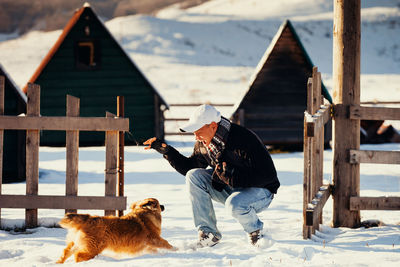 Full length of mid adult man playing with dog on snow