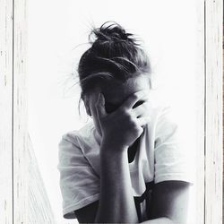 Portrait of young woman looking away against wall