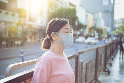 Asian woman wearing face mask standing at city street