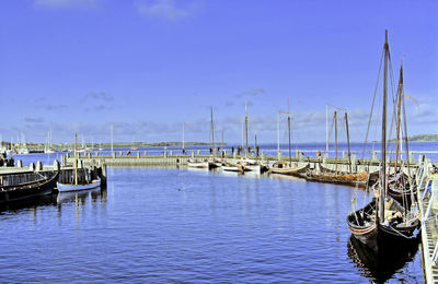 Boats moored at harbor against sky