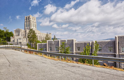 Road by buildings against sky in city