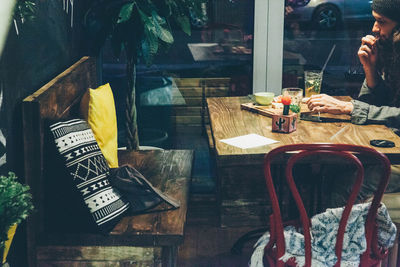 Man eating food at wooden table in restaurant