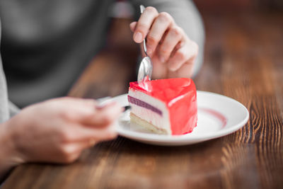 Cropped hands of woman having cake at table