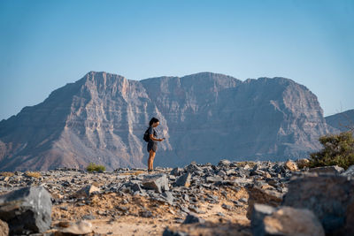Full length of man standing on rocks against mountains