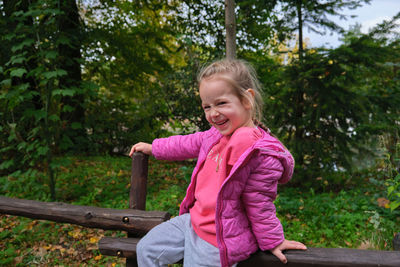 Portrait of young woman standing against trees