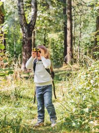 Curious boy is hiking in forest. outdoor leisure activity for kids. child looks through binoculars