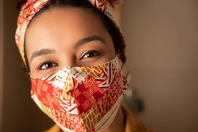 Portrait of woman wearing mask standing at home