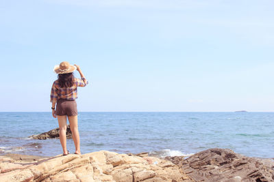 Rear view of man walking on beach against clear sky