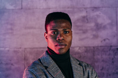 Portrait of young man standing against wall