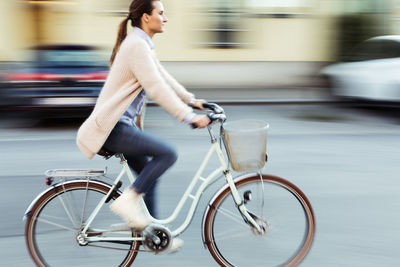 Side view of businesswoman riding bicycle on road