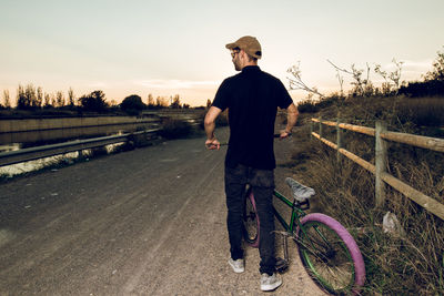 Man riding bicycle on road against sky during sunset