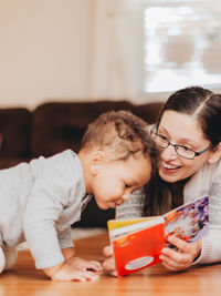 Mother reading book sitting with son at home