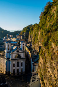 Road by buildings against clear blue sky
