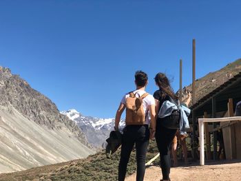 Couple looking at mountains against clear sky