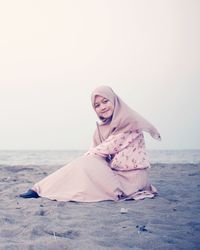 Portrait of smiling woman on beach against sky