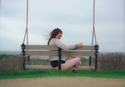 Portrait of woman sitting on swing in playground