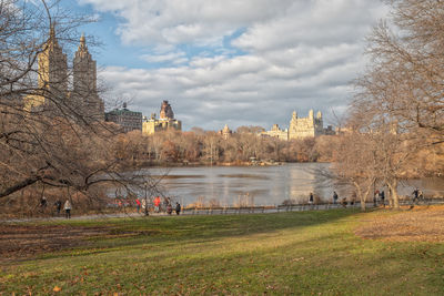 View of buildings by river against cloudy sky