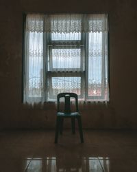 Empty chairs and table against window of house