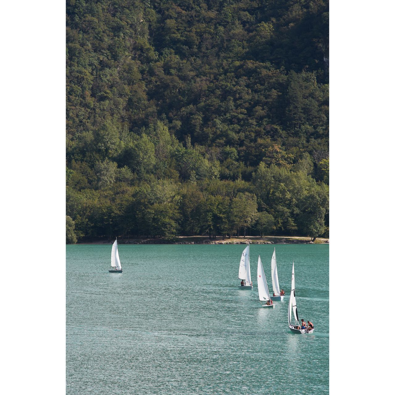 BOATS SAILING IN SEA AGAINST MOUNTAINS