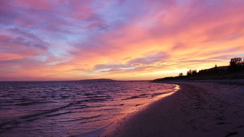 Scenic view of beach against sky at sunset