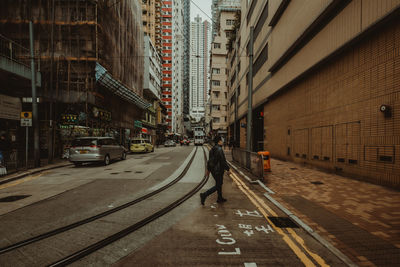 Man walking on street amidst buildings in city