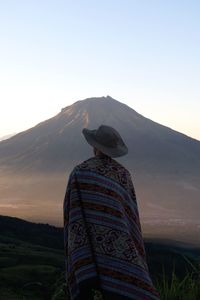 Rear view of man standing on mountain against sky