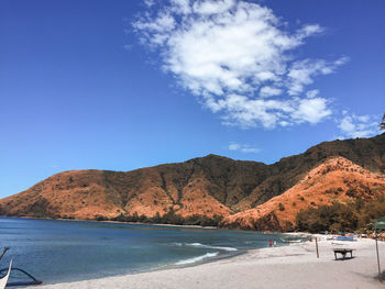 Scenic view of sea and mountains against blue sky