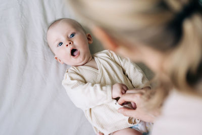 Close-up of cute baby girl lying on bed at home