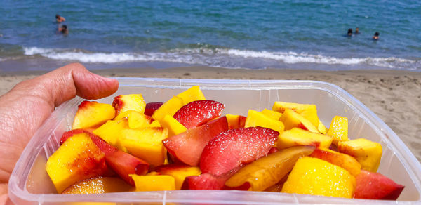 Midsection of person holding fruits at beach