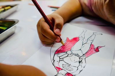 Cropped hand of boy coloring on book