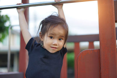 Portrait of cute girl hanging on rod