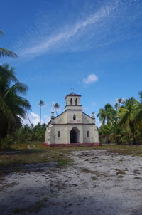 Abandonned church by building against blue sky