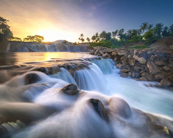Scenic view of waterfall against sky during sunset