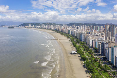 High angle view of sea and buildings against sky with long beach