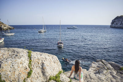 Rear view of woman by sea against clear sky