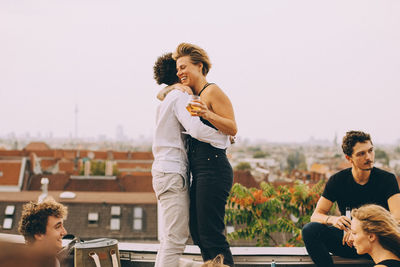 Man and woman embracing while enjoying party with friends at terrace