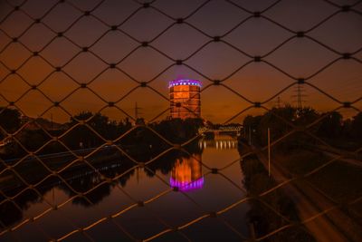 View of bridge in city seen through chainlink fence