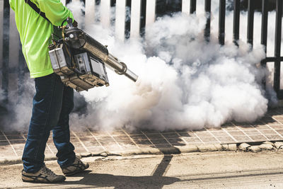 Rear view of man working on smoke emitting