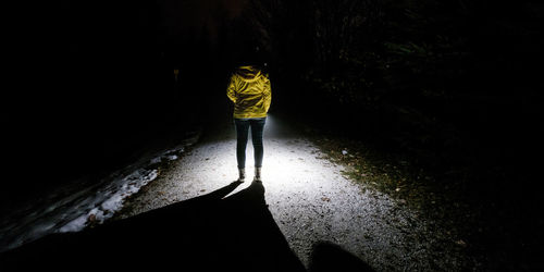 Rear view of a person walking on water at night