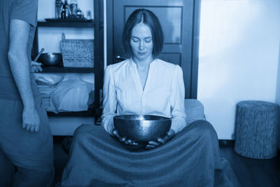 Portrait of young woman sitting on bed at home