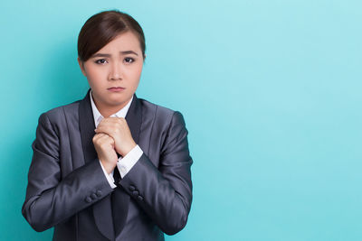 Portrait of young woman against blue background