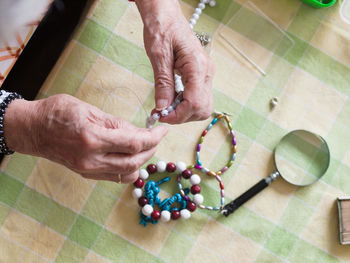 High angle view of woman making bracelet on table