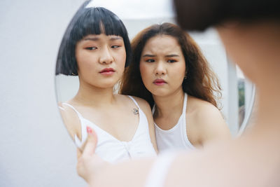 Reflection of lesbian sisters holding mirror outdoors