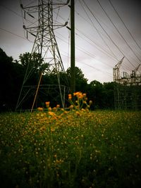 Electricity pylons on field against sky