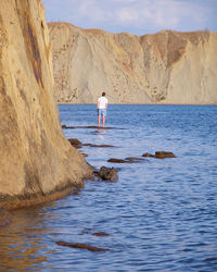 Man standing on rock by sea